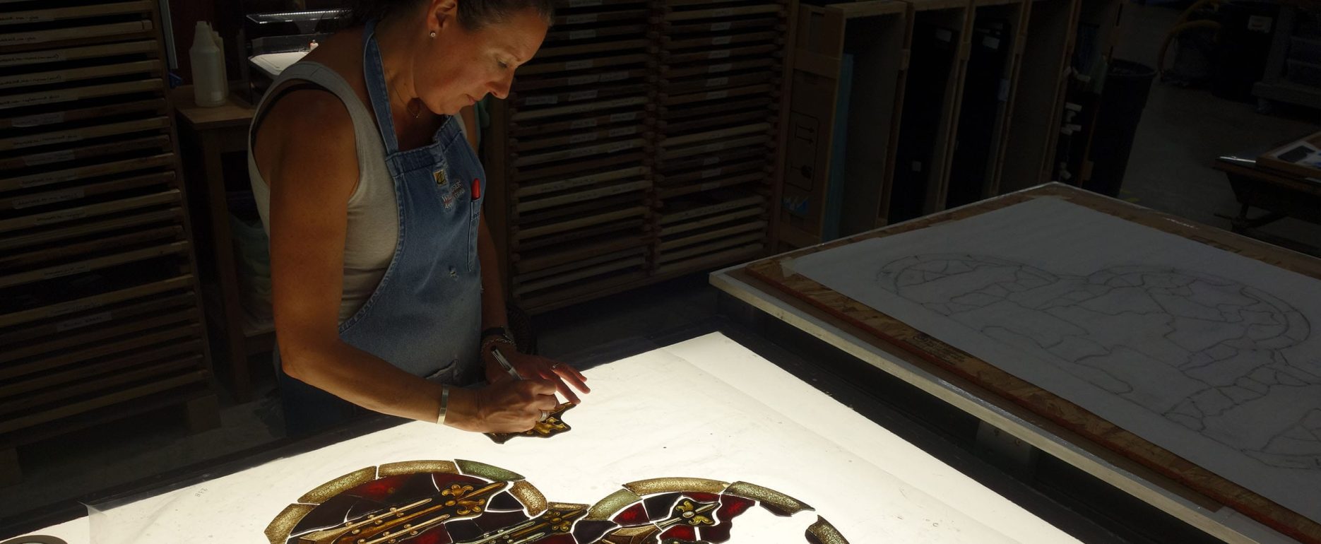 A craftswoman repairs stained glass.
