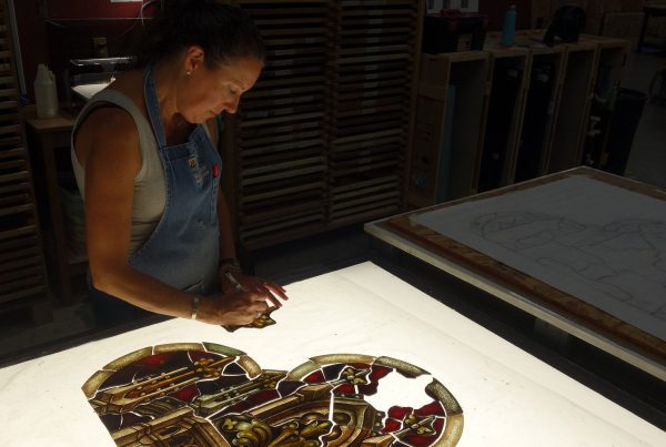 A craftswoman repairs stained glass.