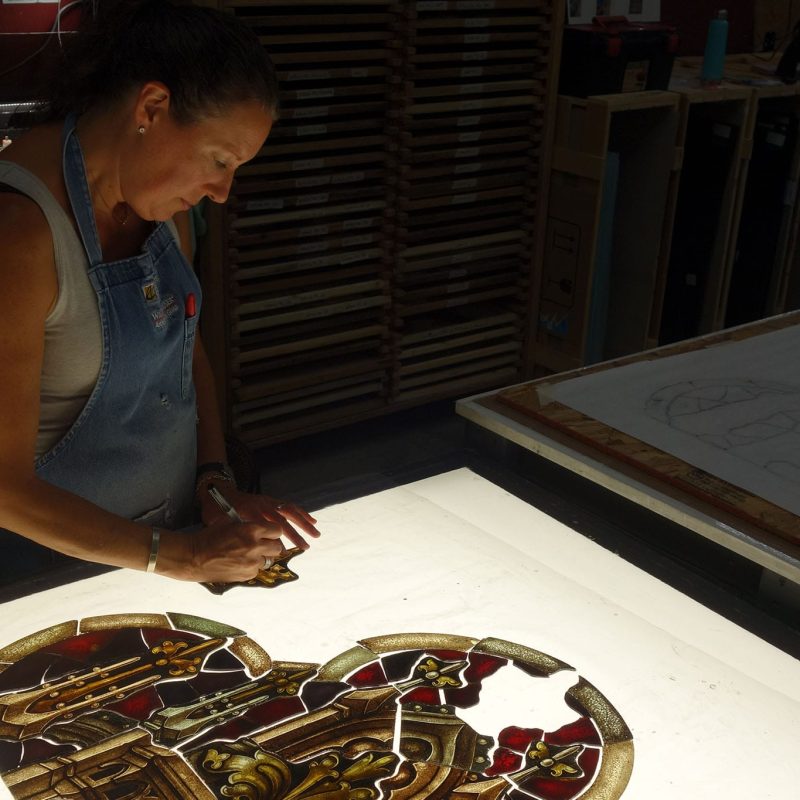 A craftswoman repairs stained glass.