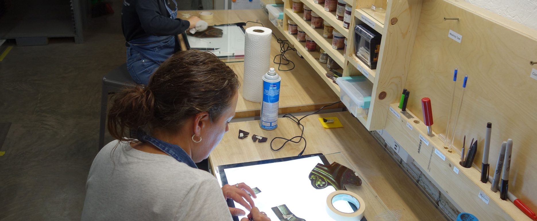 Craftswomen repair stained glass.