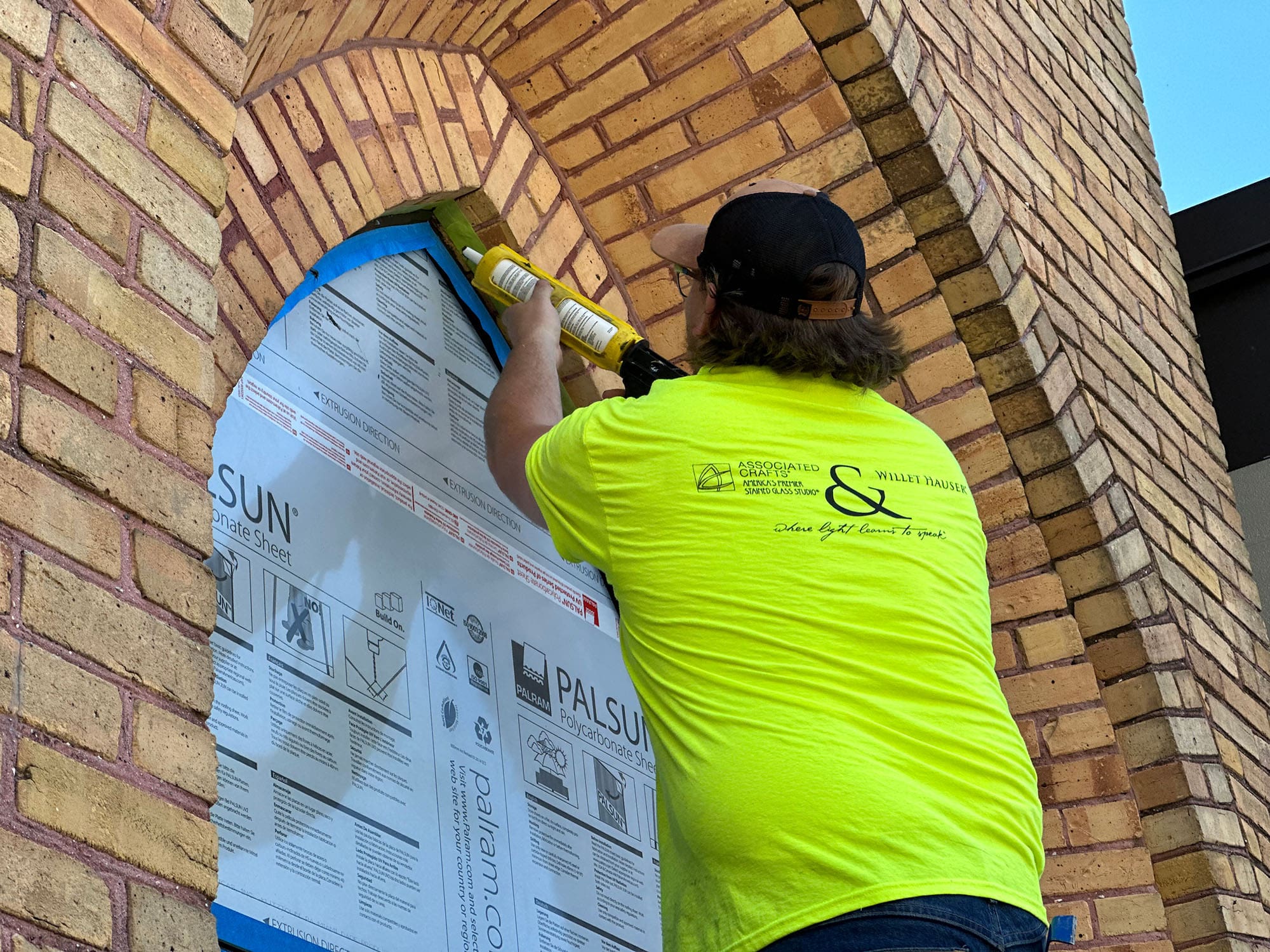 A man works on adding a protective covering to stained glass windows.