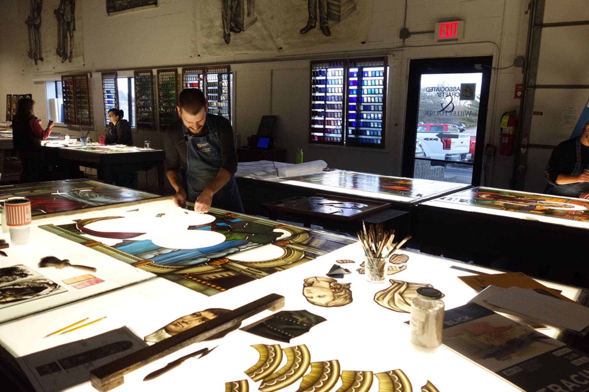 A craftsman works on a stained glass window.