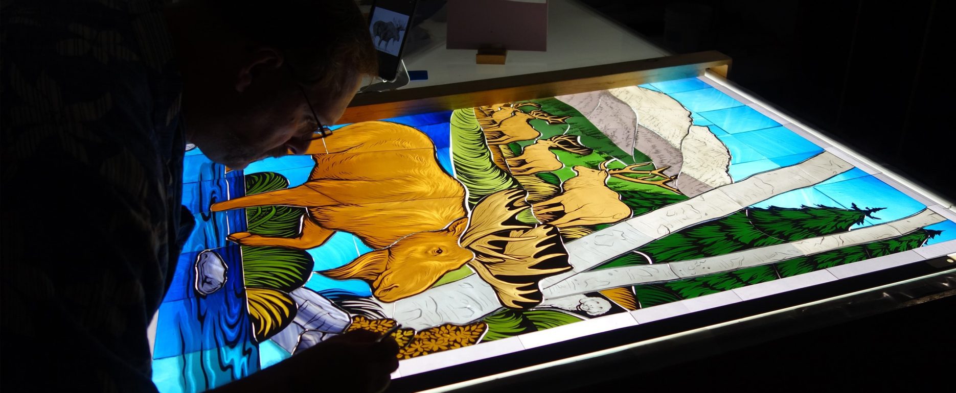 A craftsman works on a stained glass window.