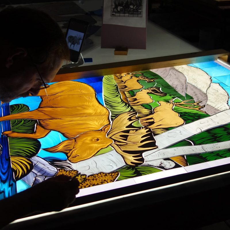 A craftsman works on a stained glass window.