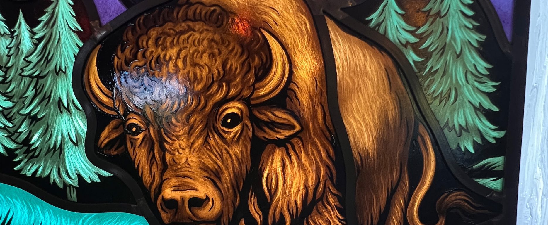 Modern architectural glass of a buffalo in the woods.