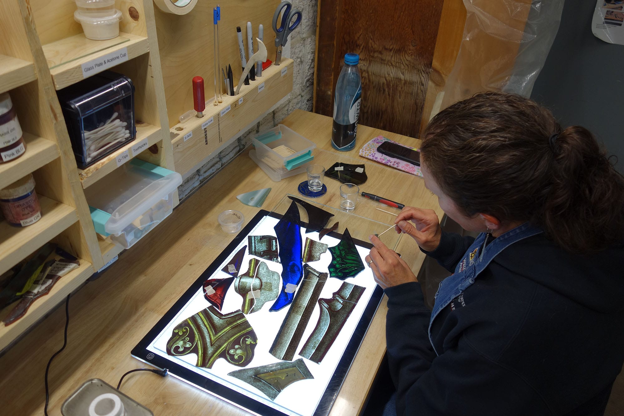 A craftswoman repairs stained glass.
