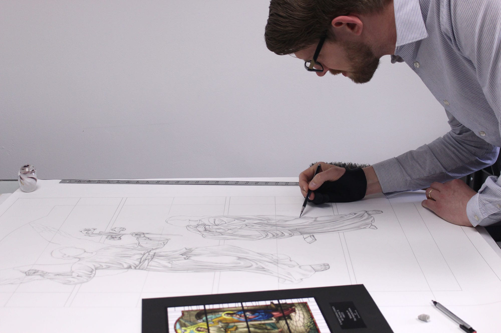 A craftsman sketches a window design for religious yet modern architectural glass.