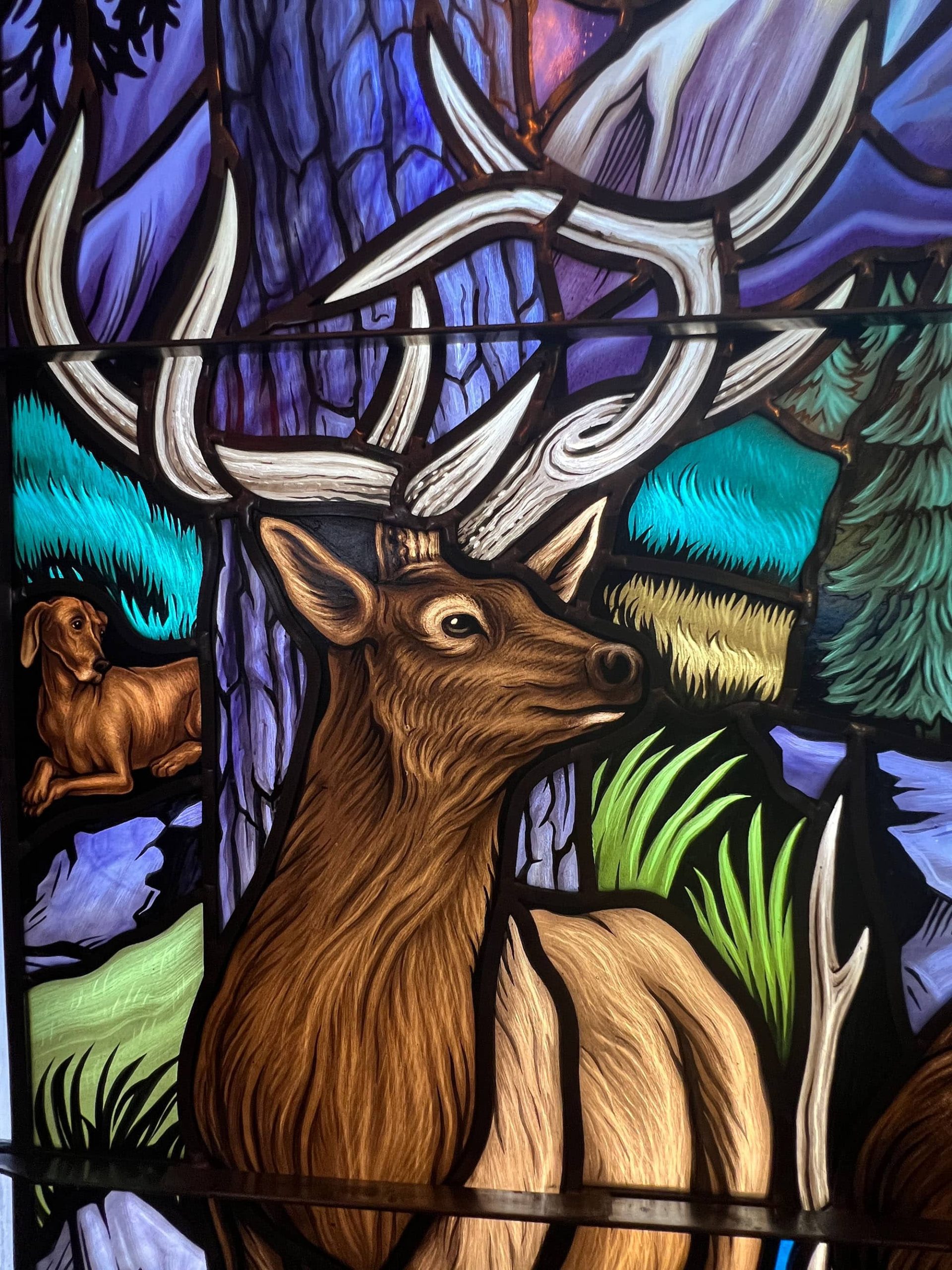 Modern architectural glass of a deer in the woods.