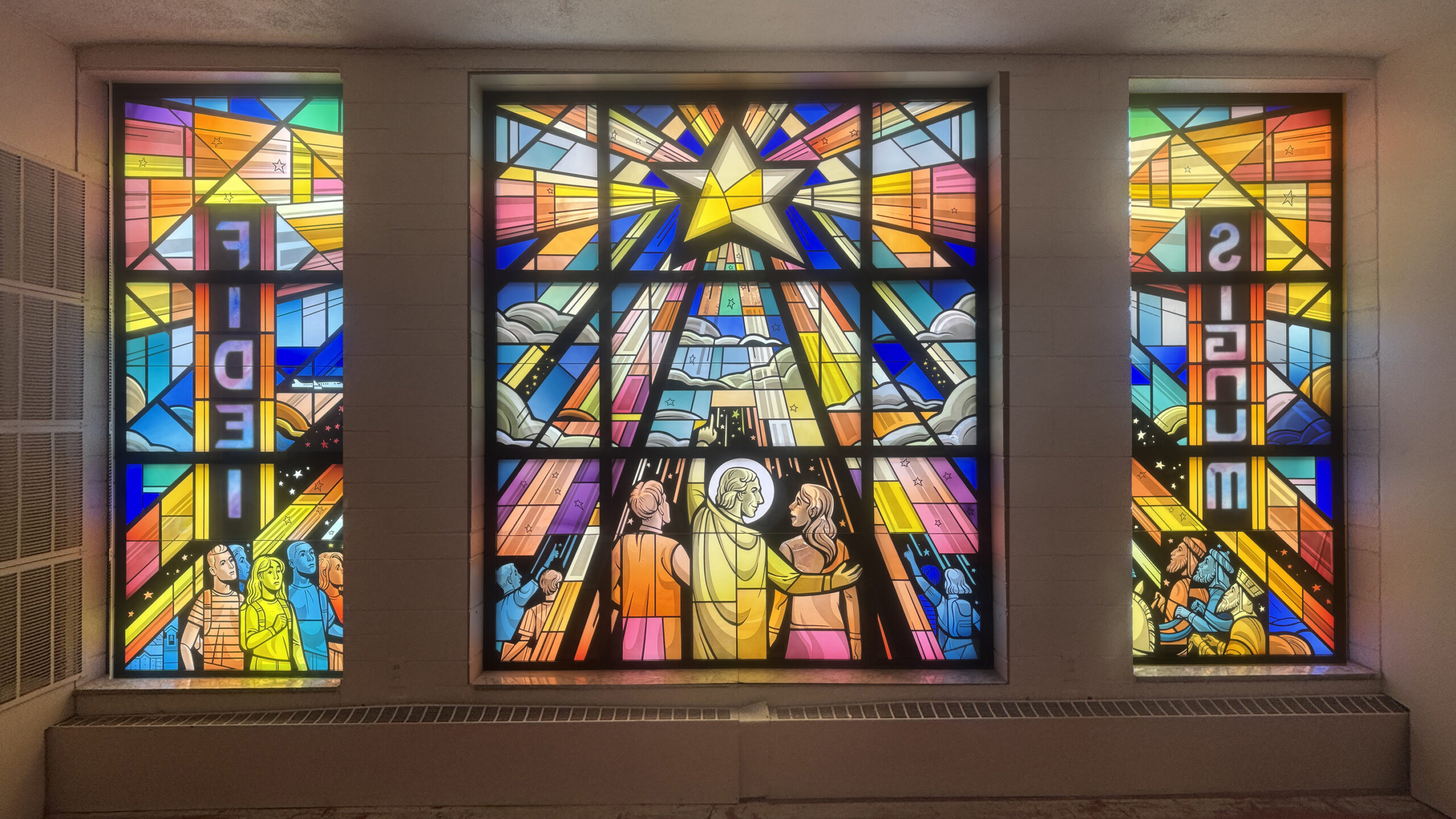 Stained glass window featuring vibrant colors and religious imagery, showcasing figures in worship and a central star, symbolizing faith and inspiration, designed by Willet Stained Glass Studios for a church setting.