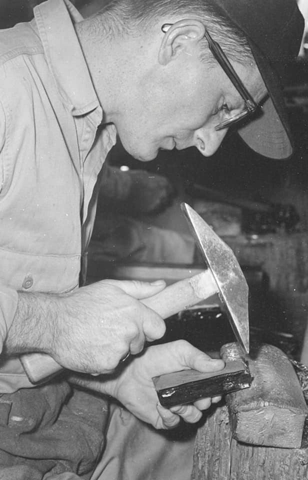 Craftsman shaping stained glass with hammer and tool, highlighting artistry and craftsmanship at Willet Stained Glass Studios.