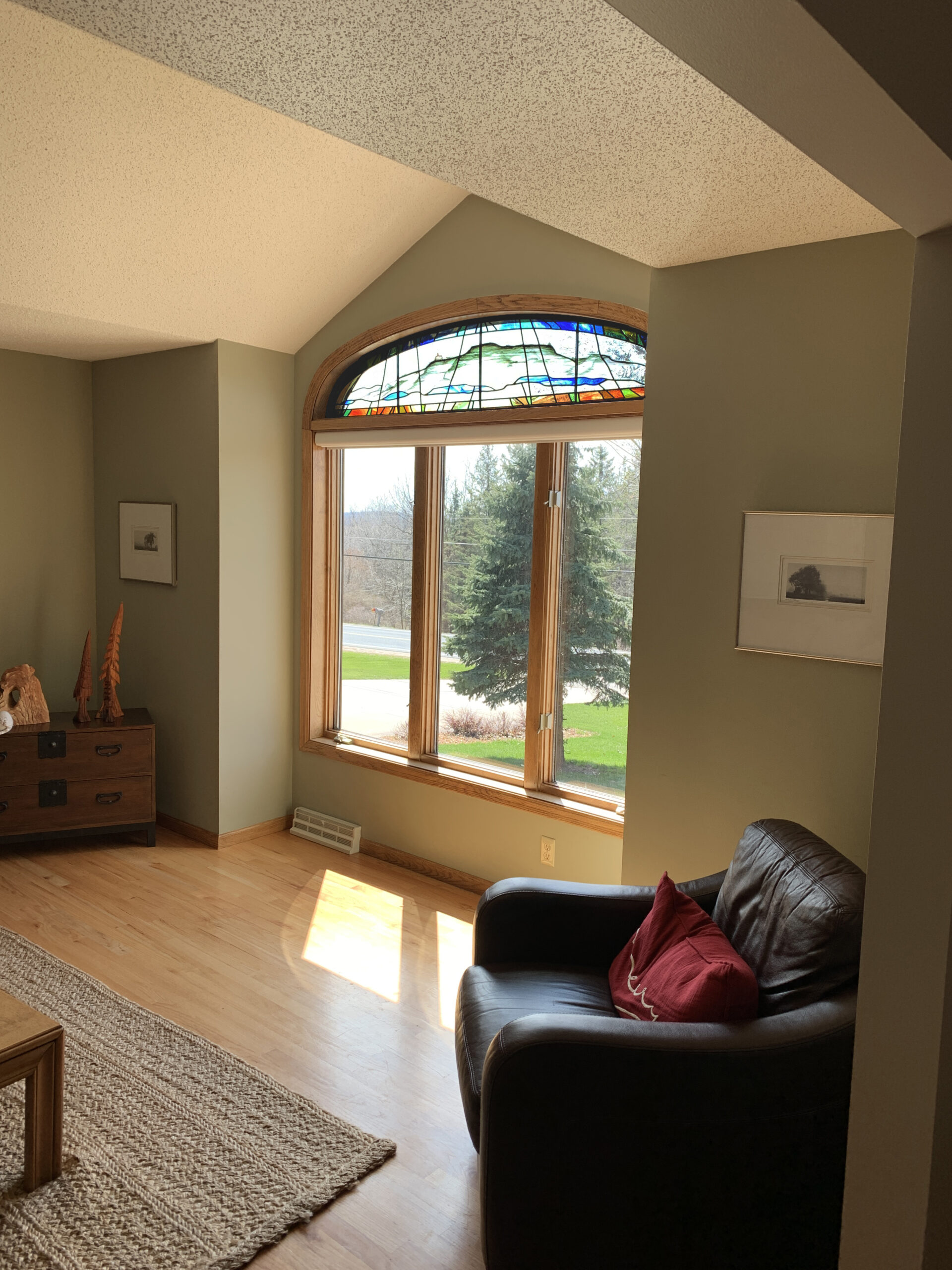 Stained glass window with vibrant colors and nature-inspired design, enhancing natural light in a cozy living space with modern furnishings.