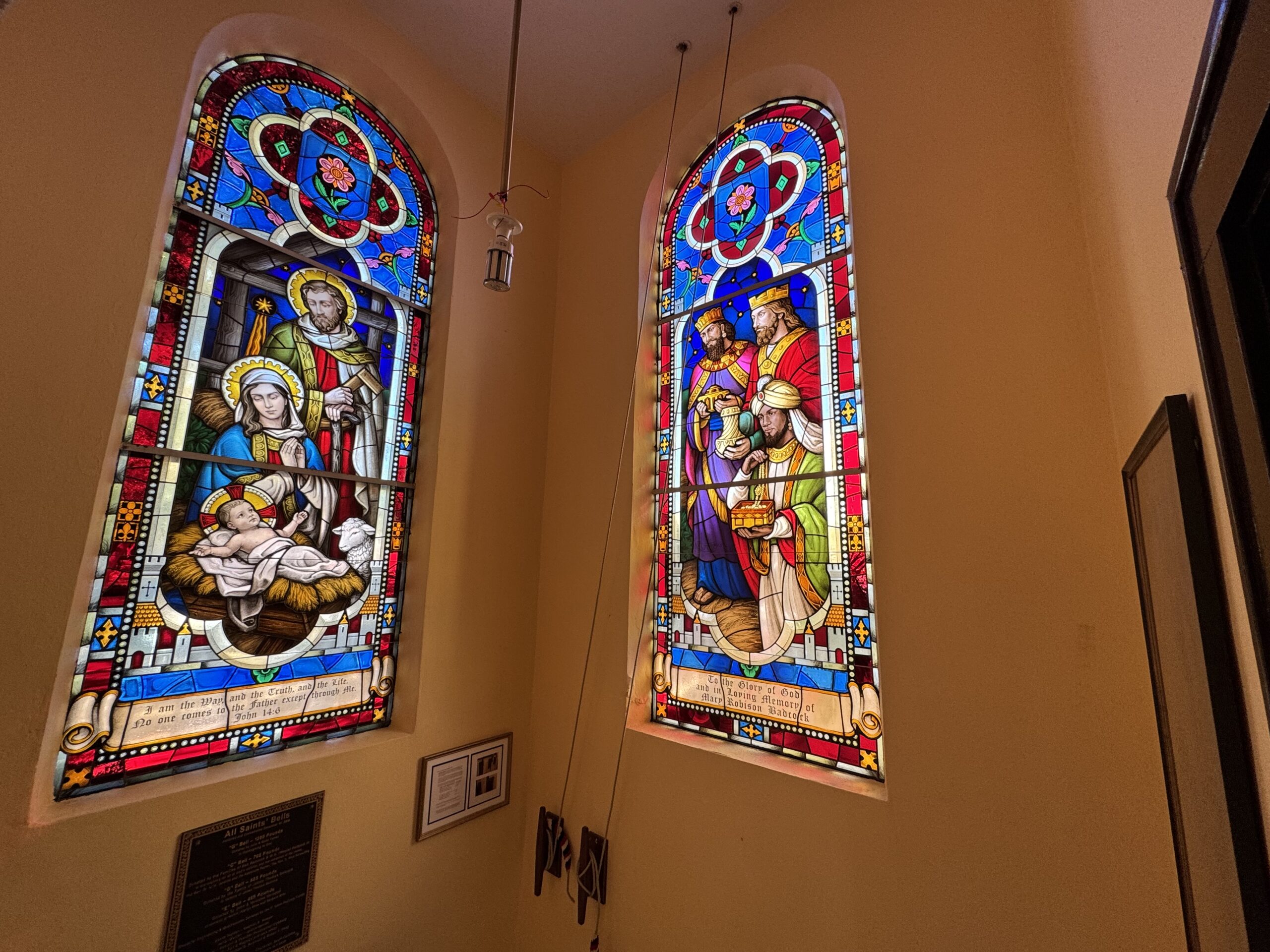 Stained glass windows depicting the Nativity scene and the Three Wise Men, showcasing vibrant colors and intricate designs, enhancing the worship environment in a church setting.