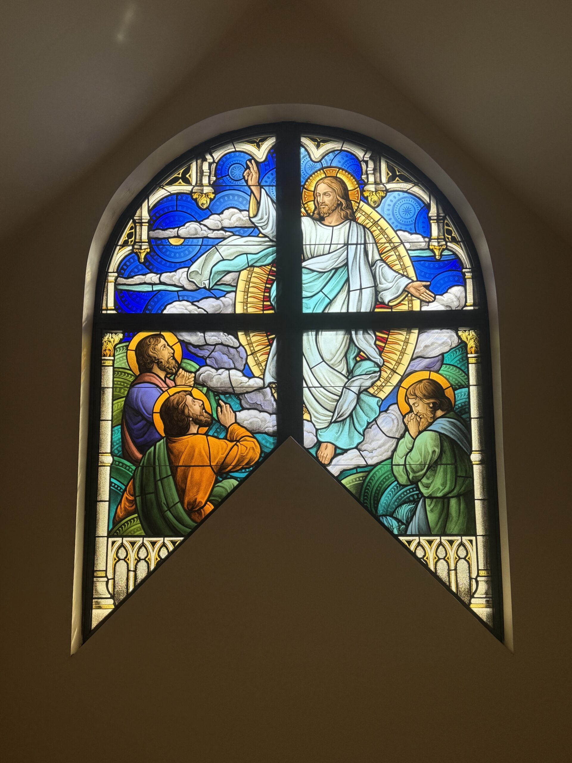 Stained glass window depicting Jesus in a radiant scene, surrounded by clouds and three figures in worship, showcasing Willet Stained Glass Studios' artistry in enhancing sacred spaces.