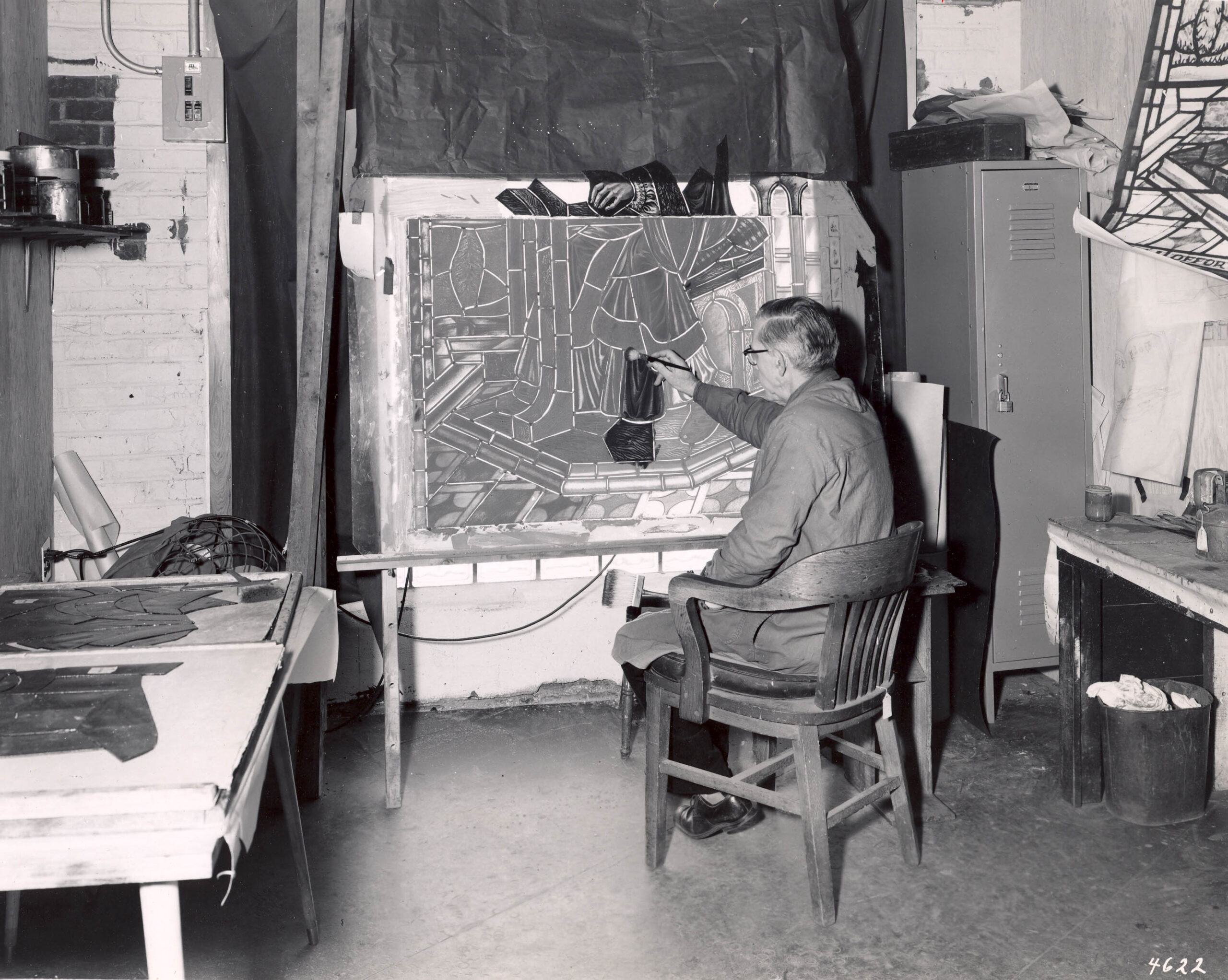 Artist working on stained glass design in studio, showcasing craftsmanship and artistry, reflecting Willet Stained Glass Studios' legacy in stained glass artistry.
