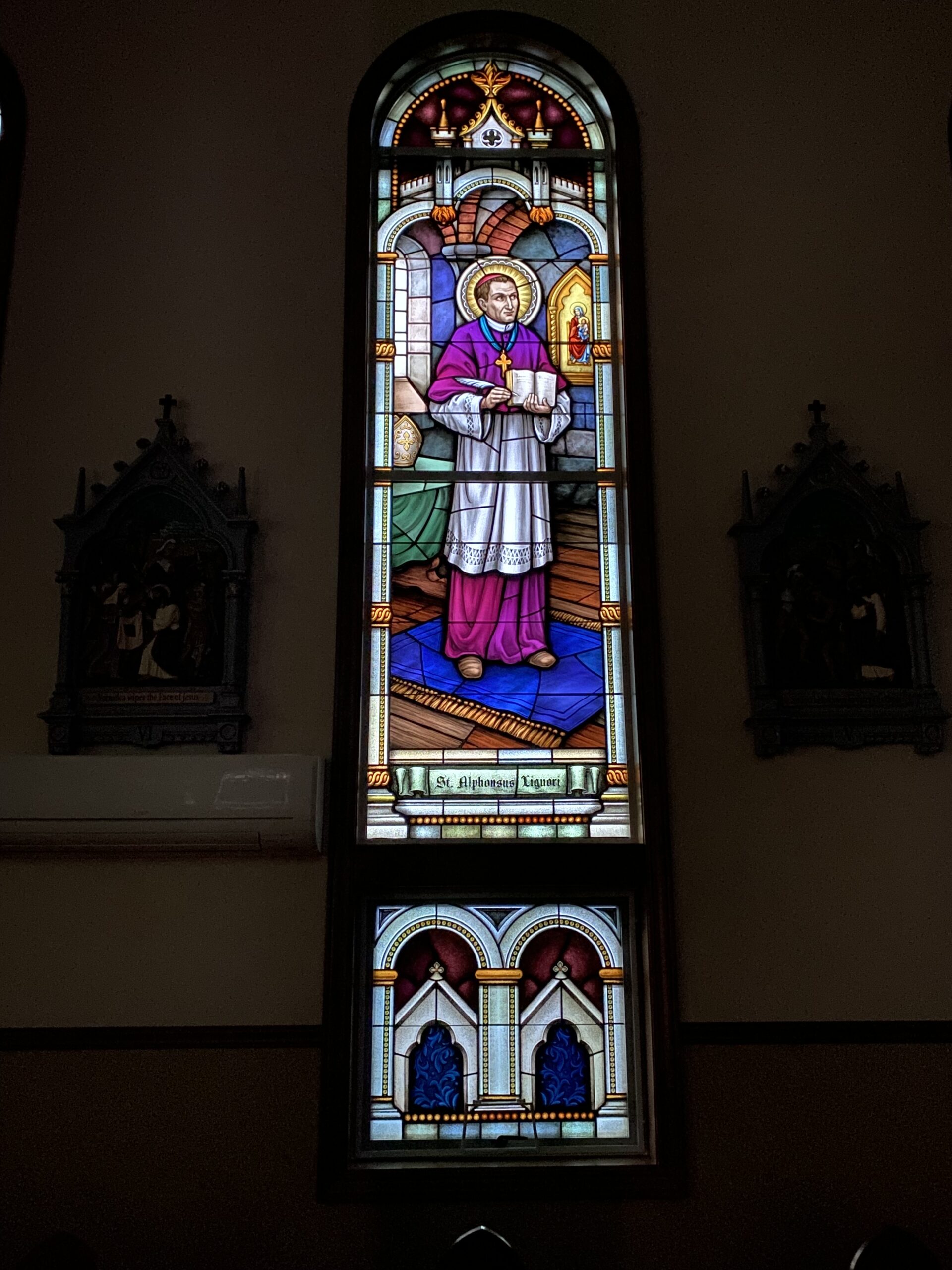 Stained glass window depicting St. Alphonsus Liguori in a church setting, showcasing vibrant colors and intricate details, reflecting the artistry of Willet Stained Glass Studios.