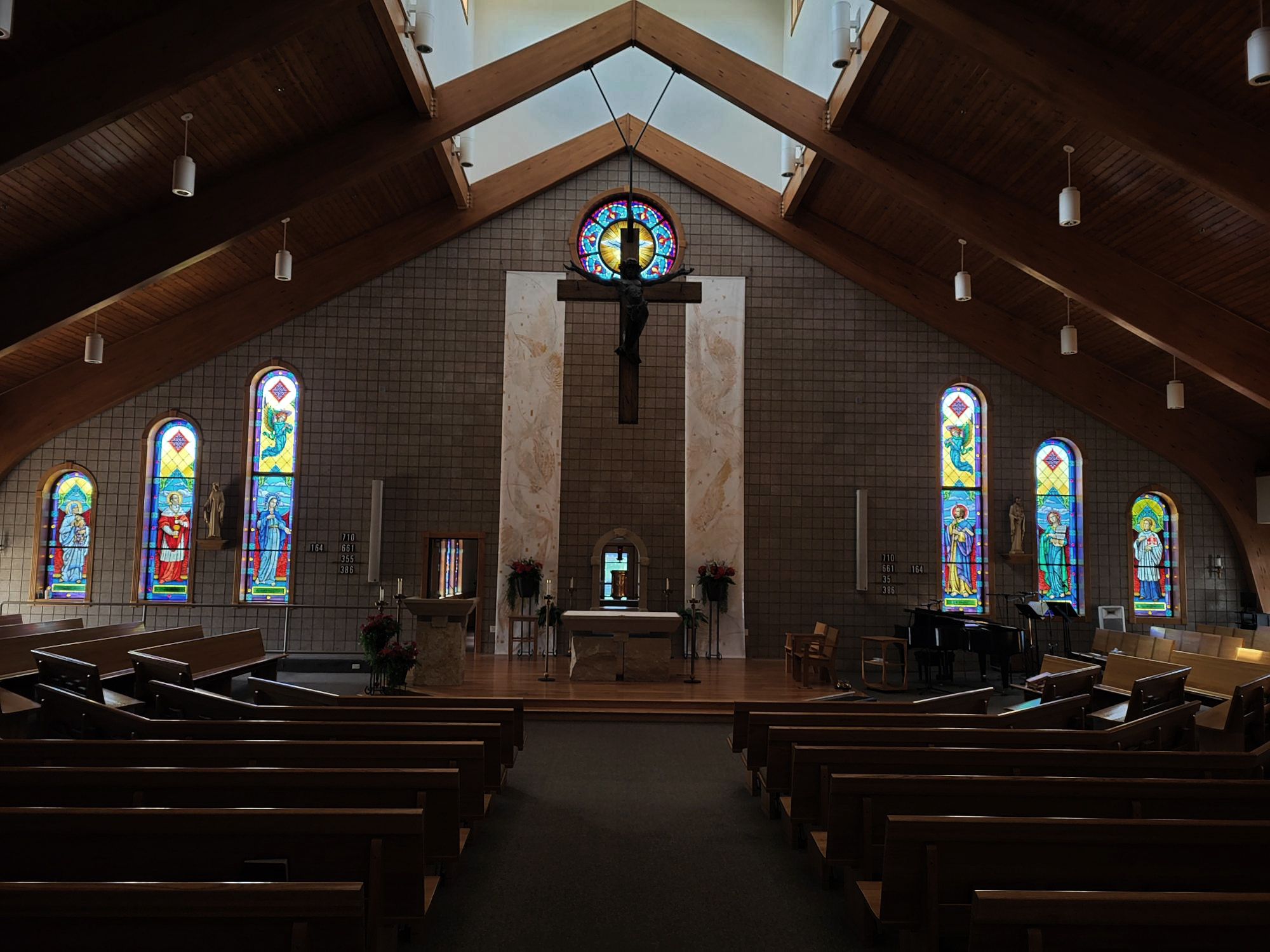 Interior of a church featuring vibrant stained glass windows depicting religious figures, wooden beams, and an altar, illustrating Willet Stained Glass Studios' craftsmanship in enhancing worship spaces.
