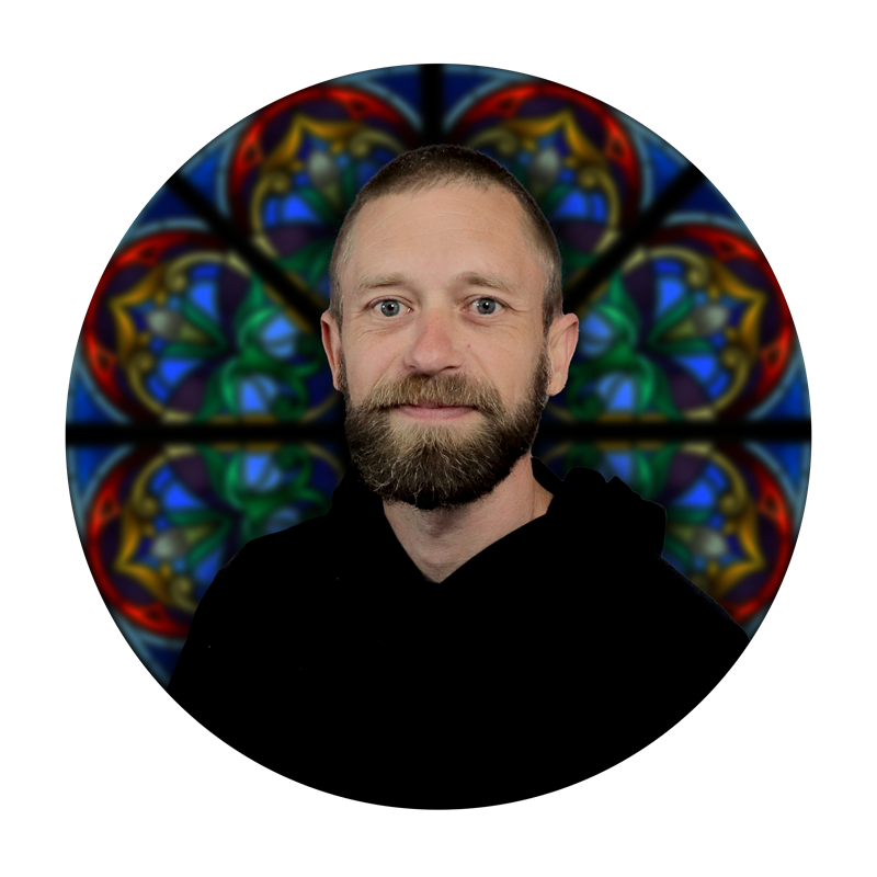 Brian Archer, Glazing Specialist at Willet Stained Glass Studios, with stained glass background featuring intricate designs and vibrant colors.