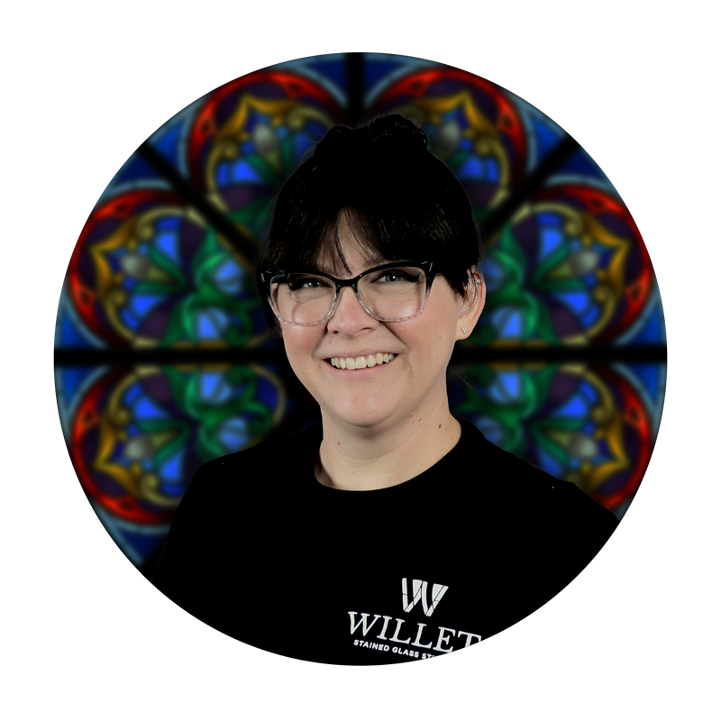 Cassandra Krueger, Special Projects Lead at Willet Stained Glass Studios, smiling in front of a colorful stained glass design.