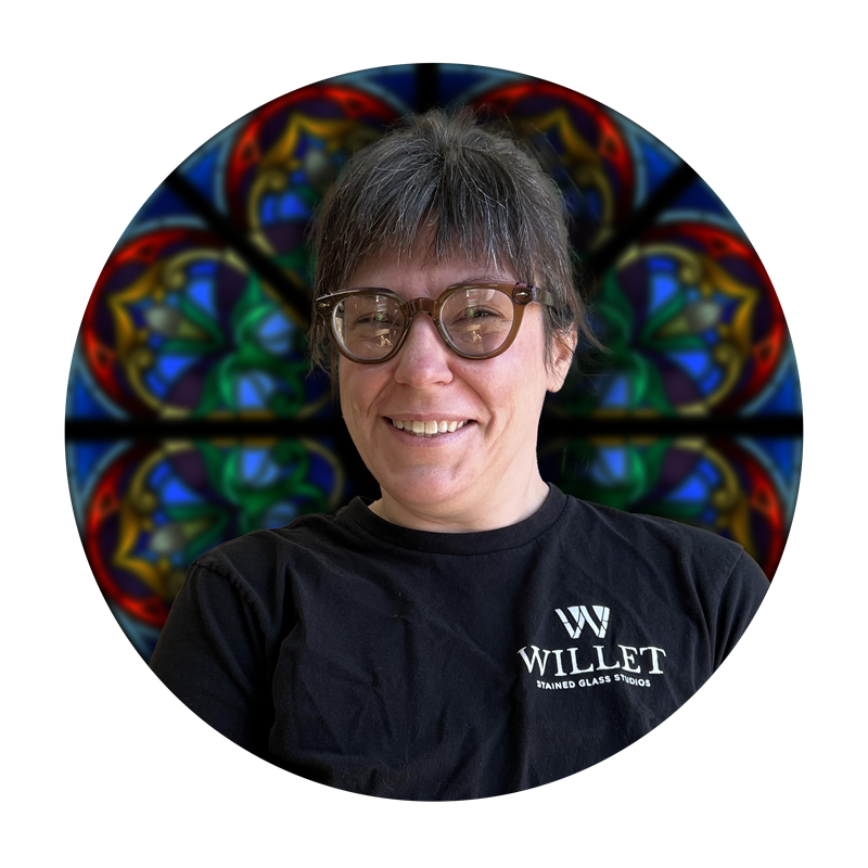 Kate Jaynes, Production Specialist at Willet Stained Glass Studios, smiling in front of a colorful stained glass backdrop.