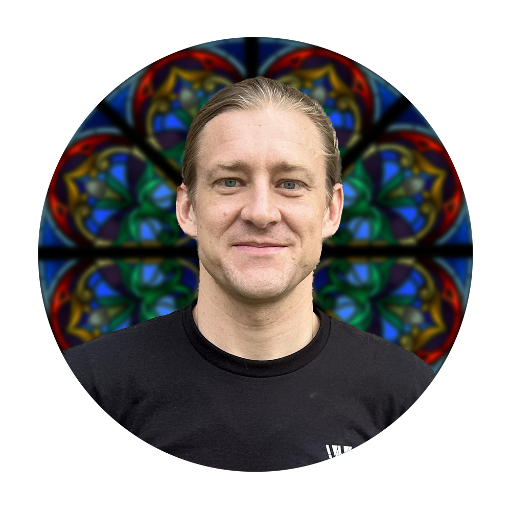 Paul Russell, Chief Operations Officer at Willet Stained Glass Studios, with a colorful stained glass window background.