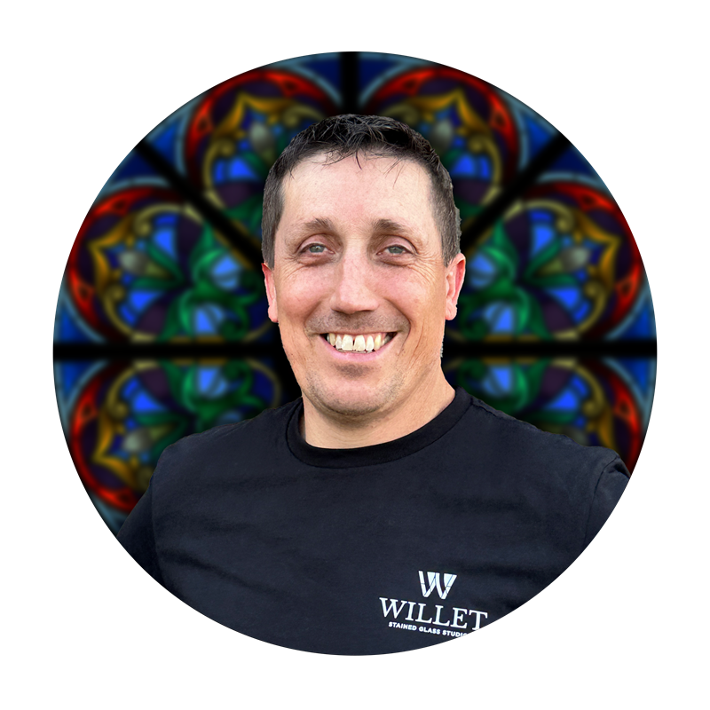 Scottie Winterton, Studio Consultant at Willet Stained Glass Studios, smiling in front of a colorful stained glass window backdrop.