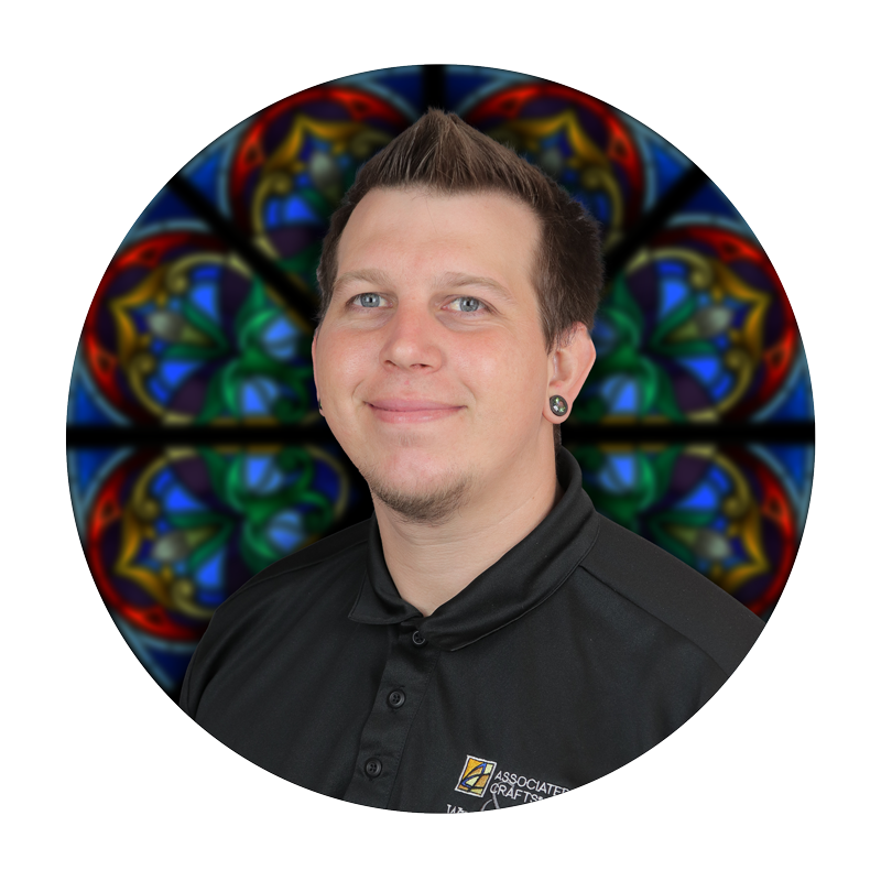 Casey Deakman, Maintenance Coordinator at Willet Stained Glass Studios, smiling in front of a colorful stained glass background.