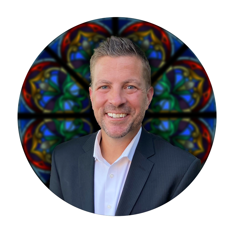 Justin Headley, Studio Consultant at Willet Stained Glass Studios, smiling in front of a colorful stained glass background.