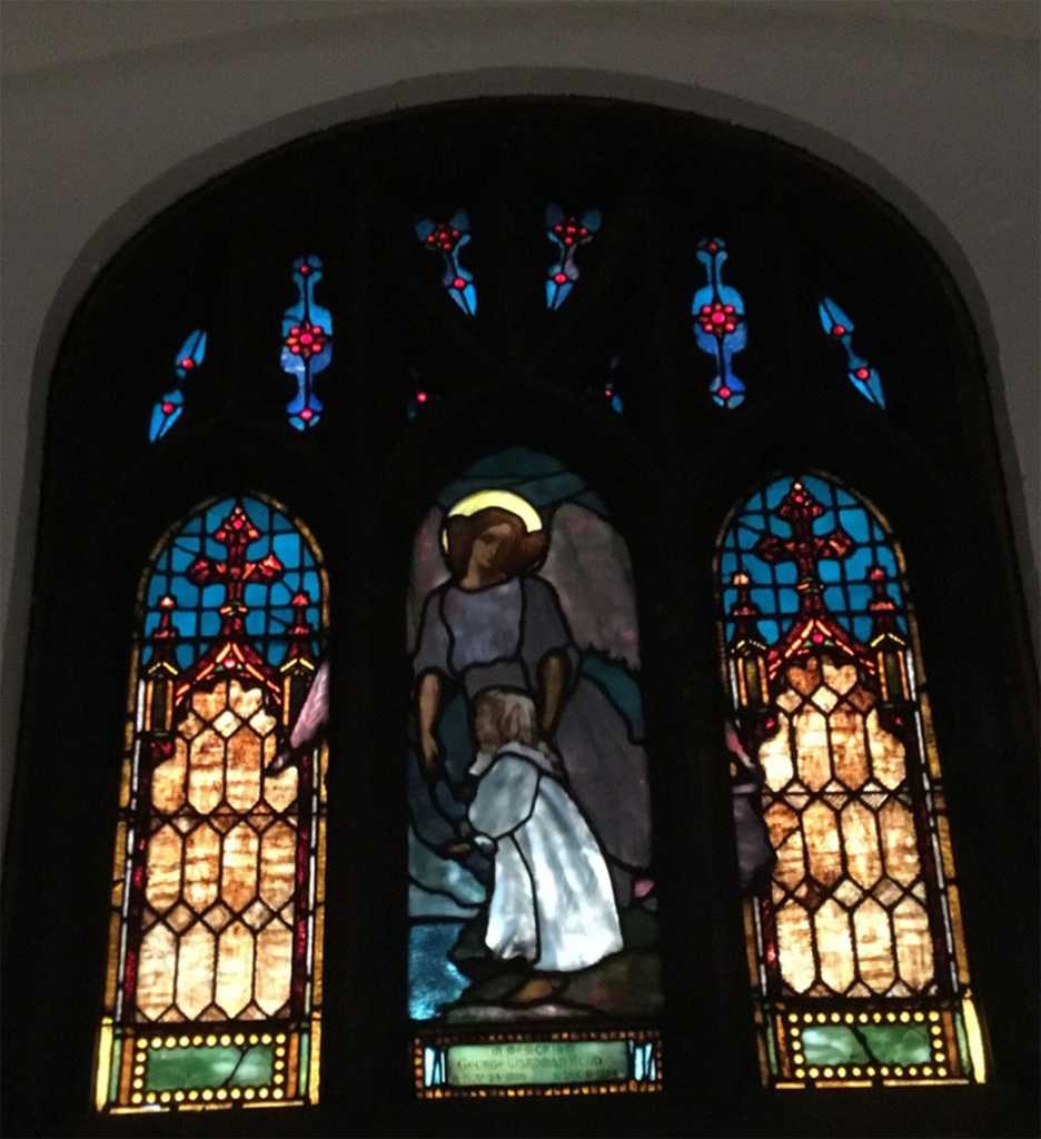 Stained glass window featuring an angel and child, showcasing intricate designs and vibrant colors, highlighting the artistry and craftsmanship important in stained glass restoration.