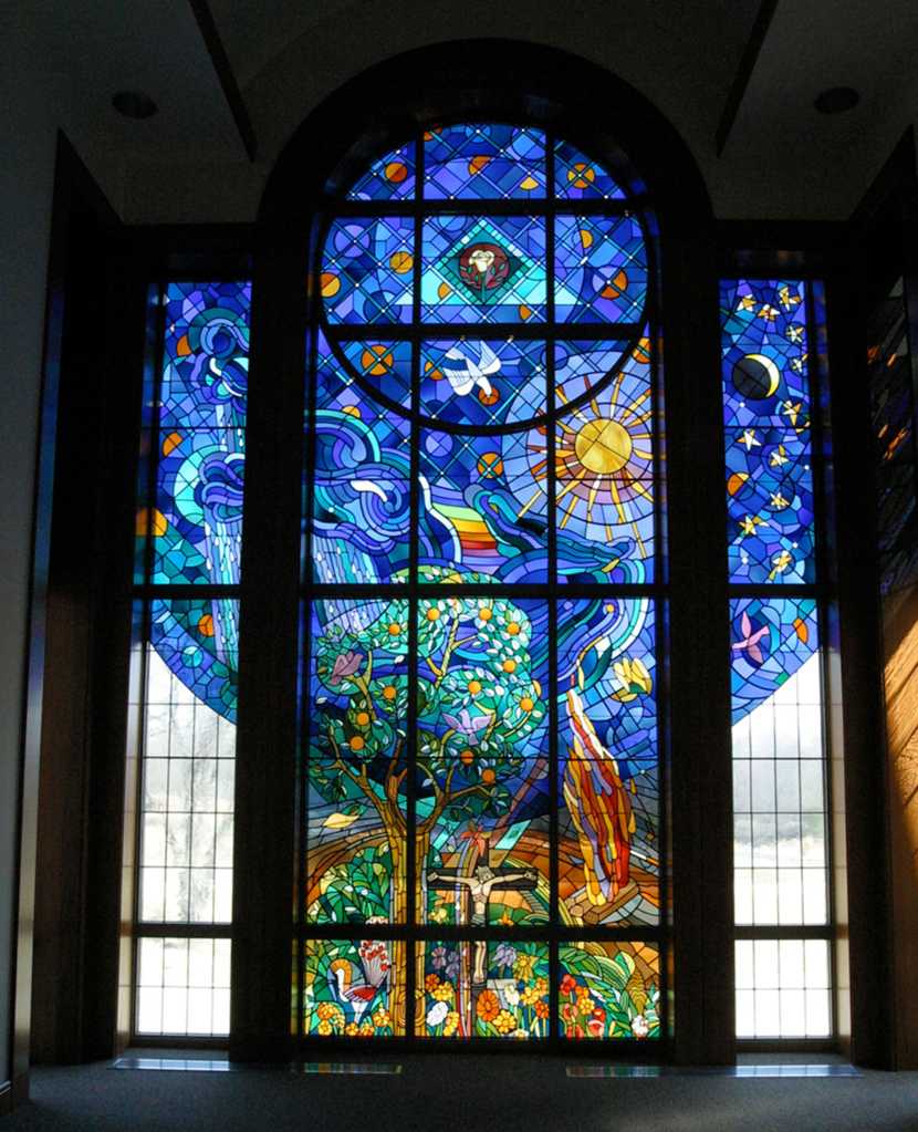 Stained glass window featuring vibrant colors and intricate designs, depicting nature, celestial elements, and symbolic imagery, highlighting the artistry of architectural art glass in modern design.