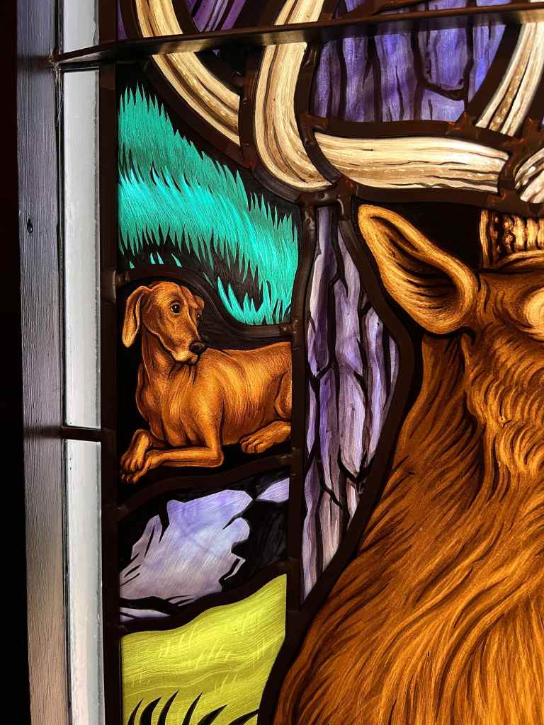 Stained glass panel featuring a stylized deer and a resting dog amidst vibrant natural elements, showcasing the artistry and craftsmanship of Willet Stained Glass Studios.