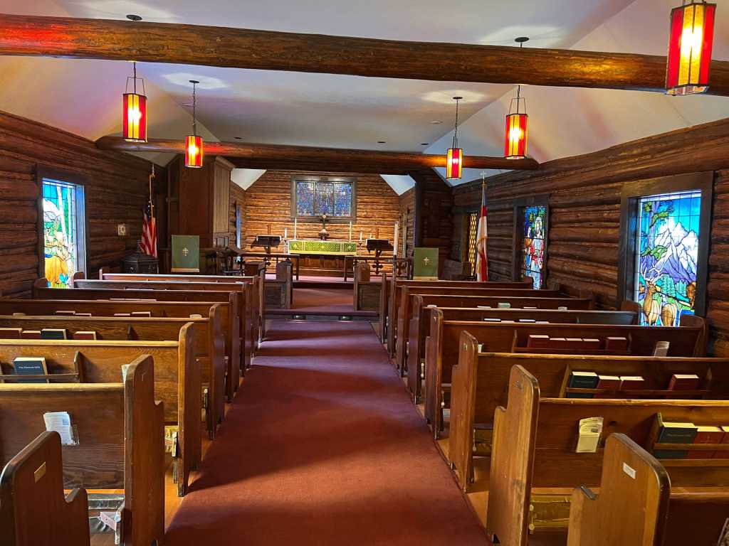 Interior view of a church featuring stained glass windows, wooden pews, and soft lighting, highlighting the spiritual ambiance and craftsmanship of Willet Stained Glass Studios.