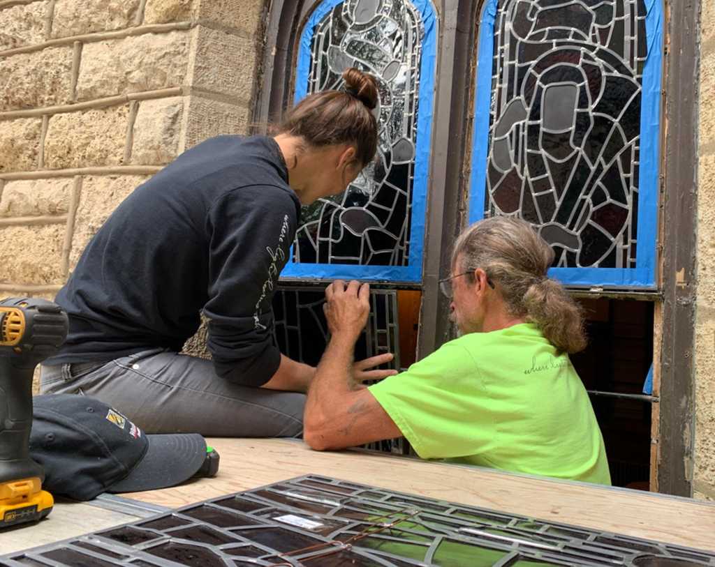 Artisans restoring church stained glass windows, showcasing craftsmanship and dedication to preserving spiritual artistry.