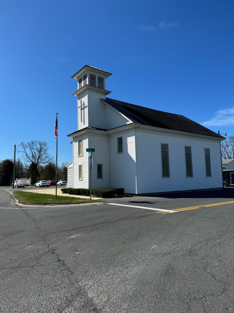 Roxana-Zion United Methodist Church in Frankford, Delaware, featuring traditional rural architecture and a prominent cross, surrounded by a clear blue sky.
