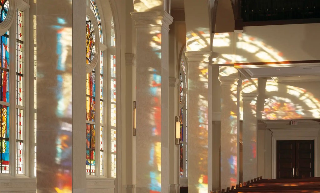 Stained glass windows casting colorful reflections on church walls, showcasing artistry and spiritual significance in a sacred space.
