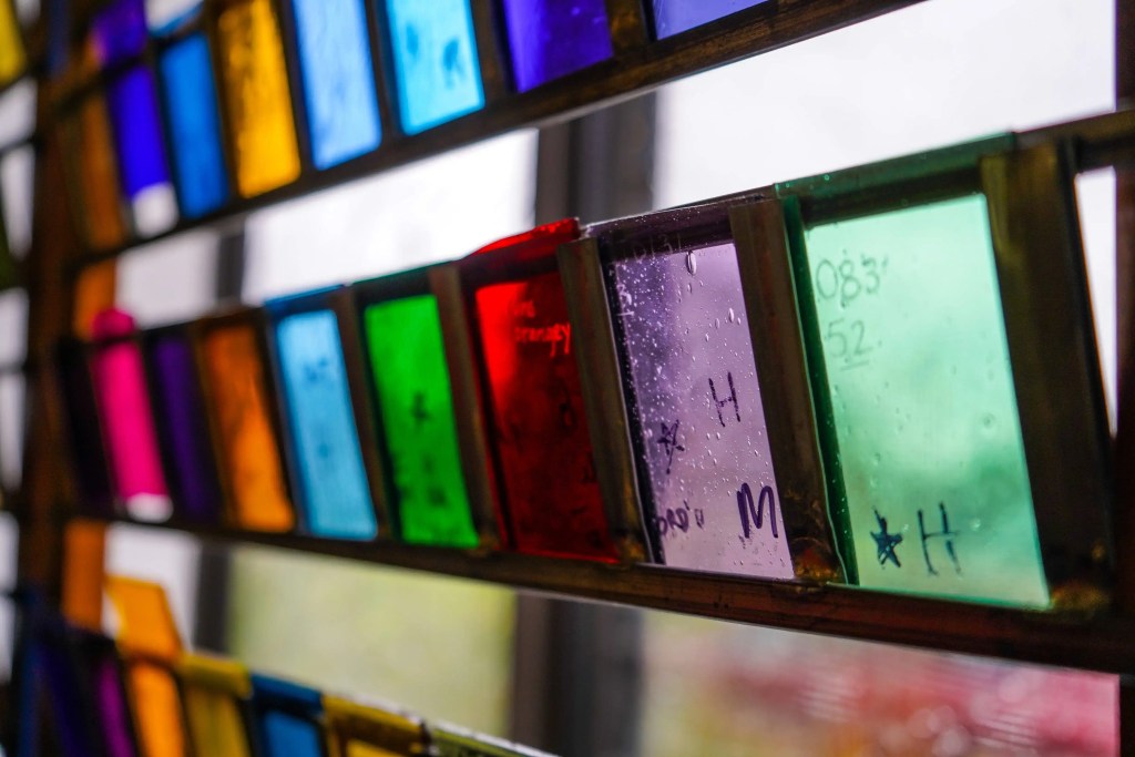 Colorful pieces of cathedral glass in various hues, showcasing craftsmanship and artistry relevant to stained glass window projects.