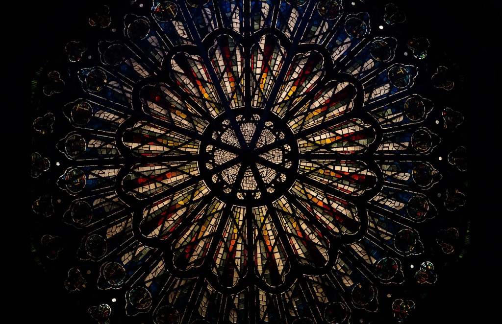 Stained glass rose window featuring intricate patterns and vibrant colors, symbolizing artistry and cultural heritage, relevant to preservation and restoration efforts.