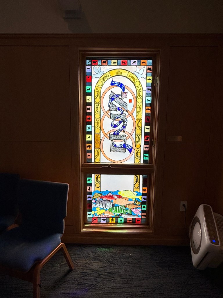 Stained glass window depicting Hebrew text and colorful animal motifs, located in Congregation Beth Israel, a historic synagogue in Charlottesville, VA.