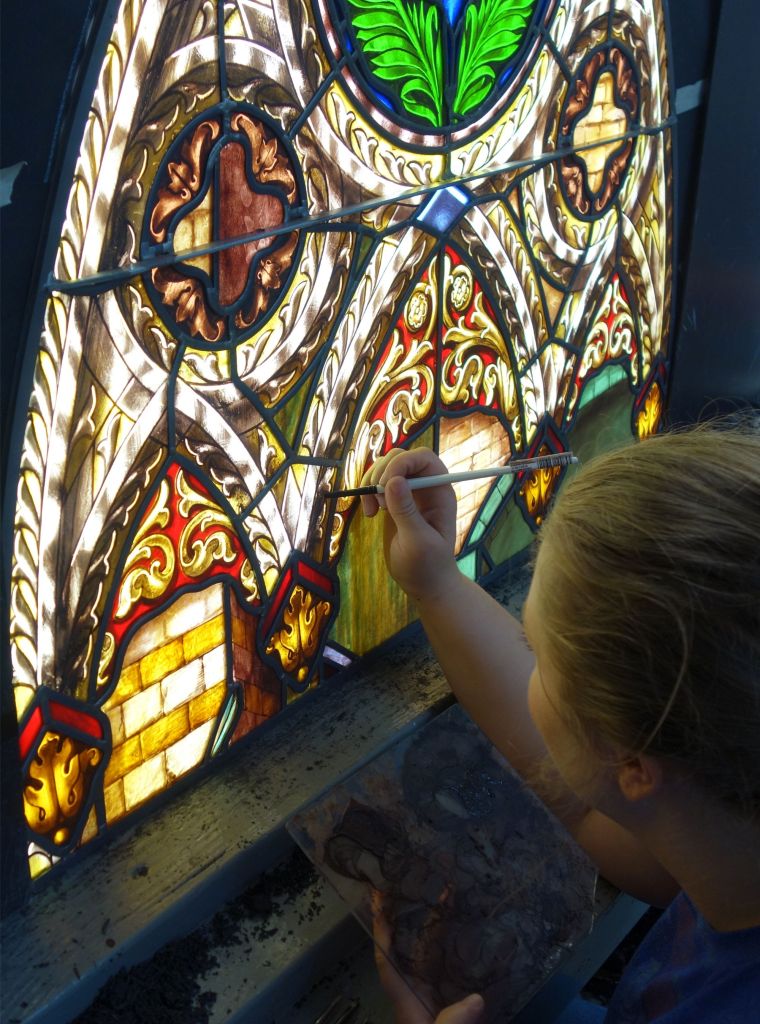 Artist meticulously restoring a stained glass window, showcasing vibrant colors and intricate designs, emphasizing the craftsmanship and spiritual significance of stained glass in worship.