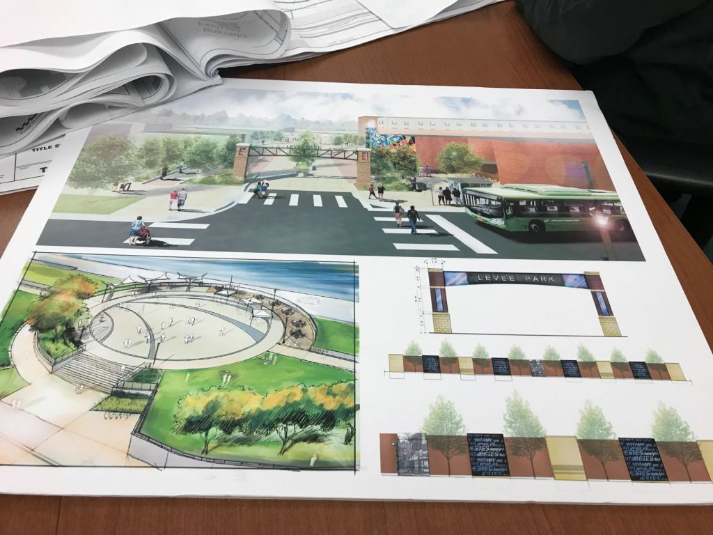 Architectural design plans for Levee Park, featuring a pedestrian-friendly layout, a bus stop, and a circular gathering space with trees and seating areas.