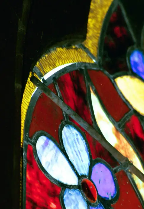Close-up of stained glass panel featuring colorful floral design, highlighting structural details and lead came, relevant to stained glass restoration techniques.