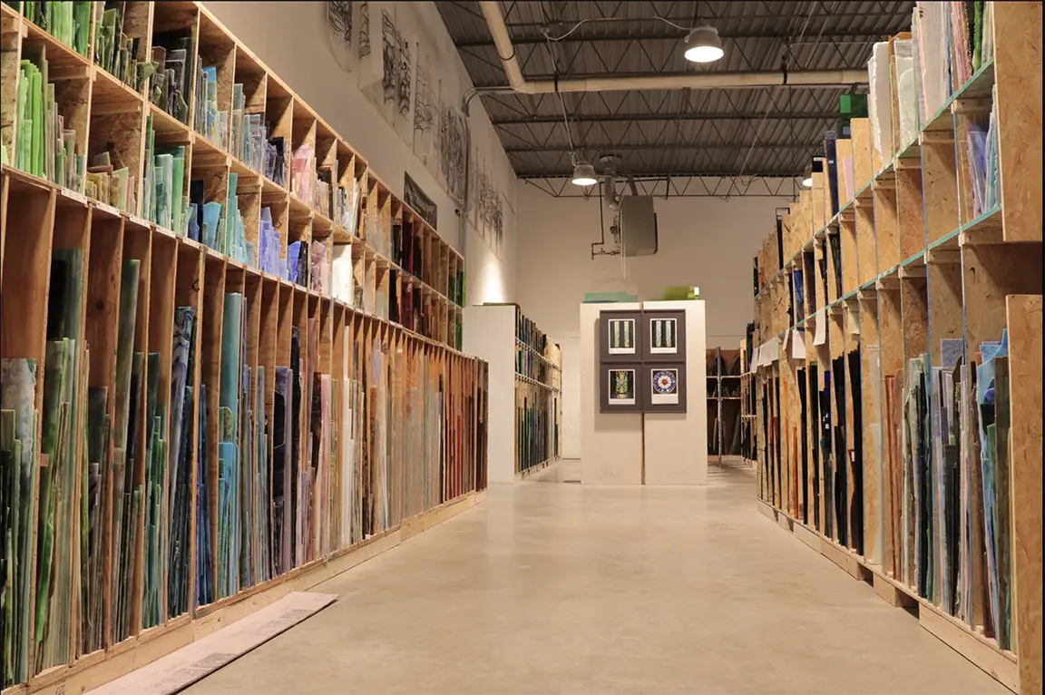 Interior of Willet Stained Glass Studios showcasing shelves filled with various stained glass materials and framed samples on display, emphasizing material selection for stained glass projects.