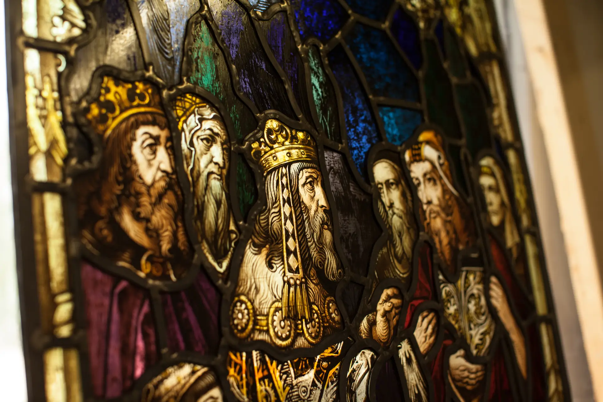 Stained glass window depicting historical figures, including a crowned king, illustrating the artistry and craftsmanship involved in stained glass restoration and preservation at Willet Stained Glass Studios.
