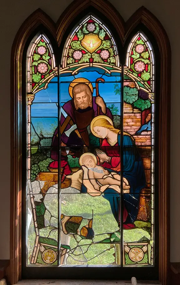 Detailed stained glass window depicting religious scene, requiring emergency stabilization and repair.