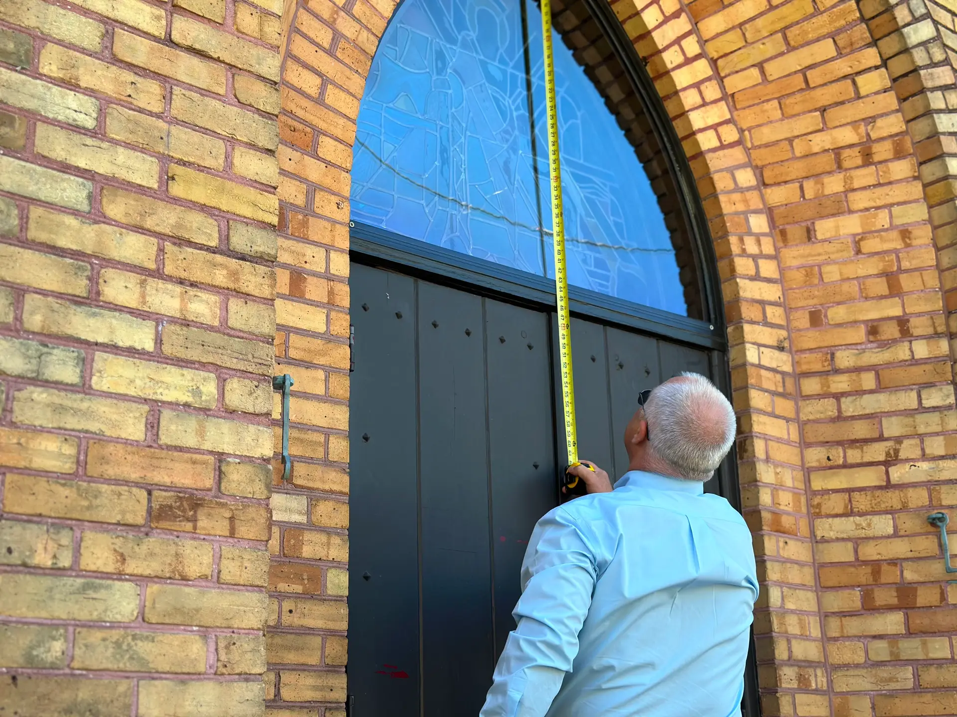 Measuring stained glass window for protective glazing installation by Willet Studios.