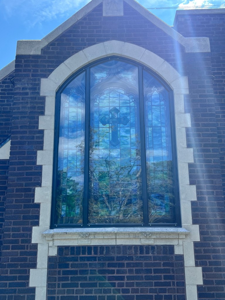 Restored stained glass window with cross design in church architecture by Willet Studios.