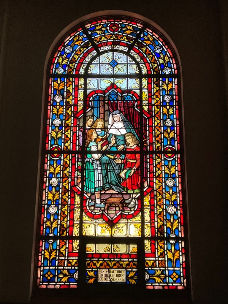 Detailed stained glass window depicting a religious figure and children, showcasing Willet Studios' restoration work